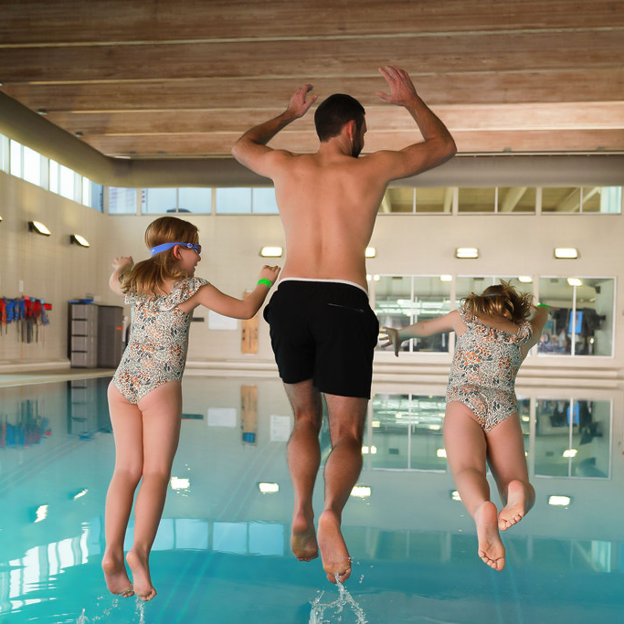 Dad and kids jump in YMCA swimming pool